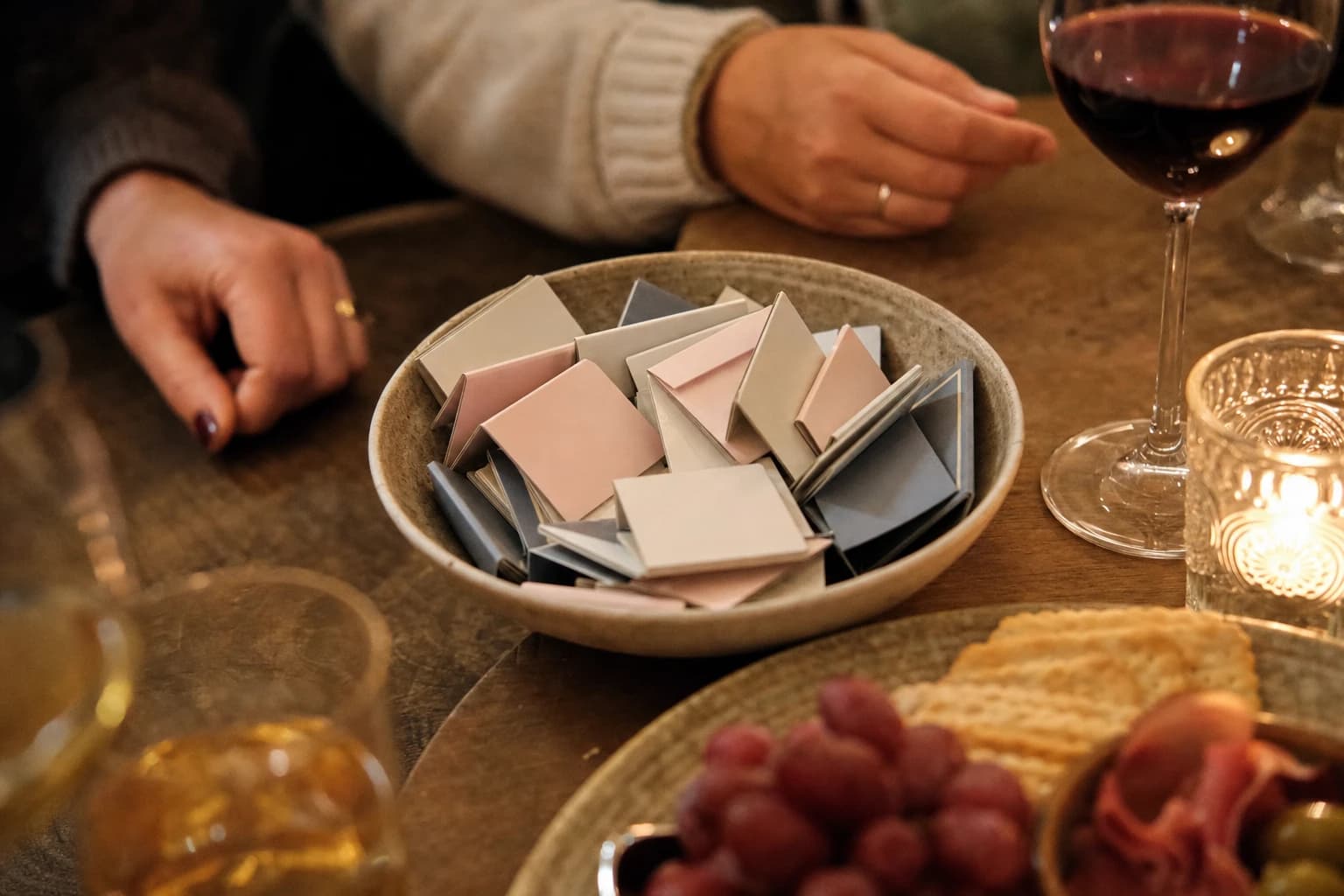 Small bowl of conversation prompt cards beside snacks and drinks on a party table