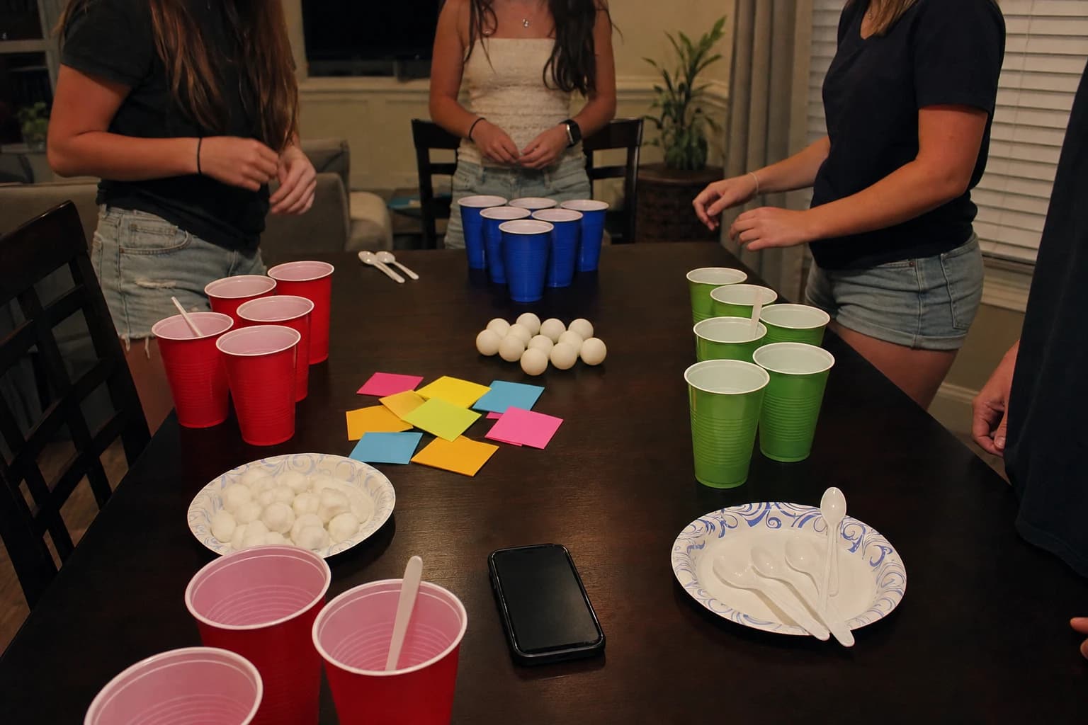 Teen party table set up with cups spoons sticky notes and ping pong balls for minute games
